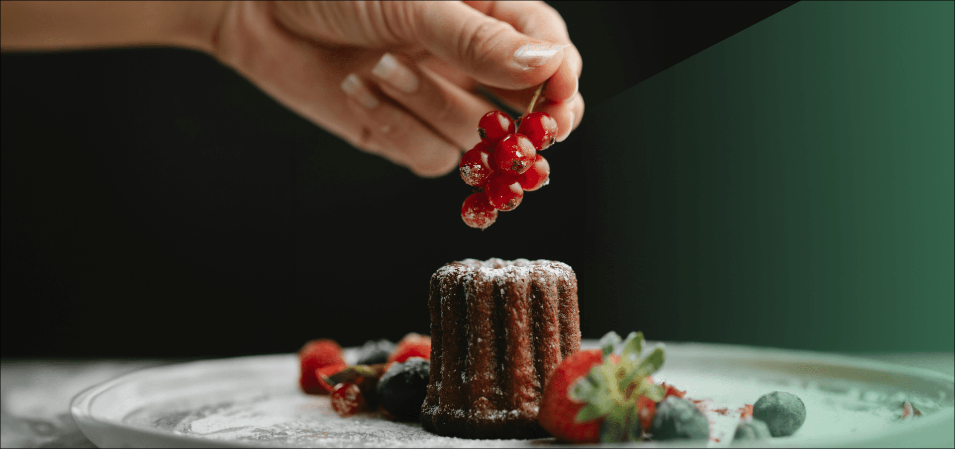 Hand met rode bessen op een chocolade dessert 