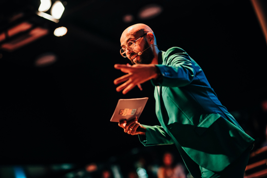 Karim Amghar in groene colbert met kaart in hand sprekend